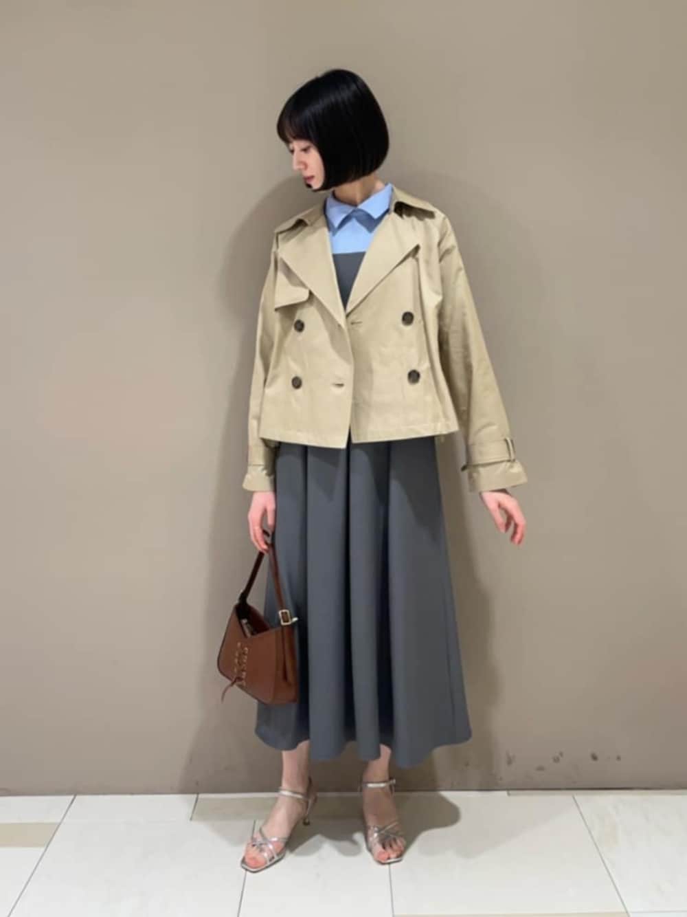 グレー系のワンピース、ベージュ系のトレンチコートを着用したレディースの春コーディネートの1枚目の写真