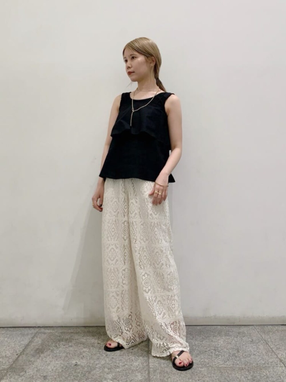 ブラック系のタンクトップ、ゴールド系のサンダル、ホワイト系のその他パンツを着用したレディースの春コーディネートの1枚目の写真