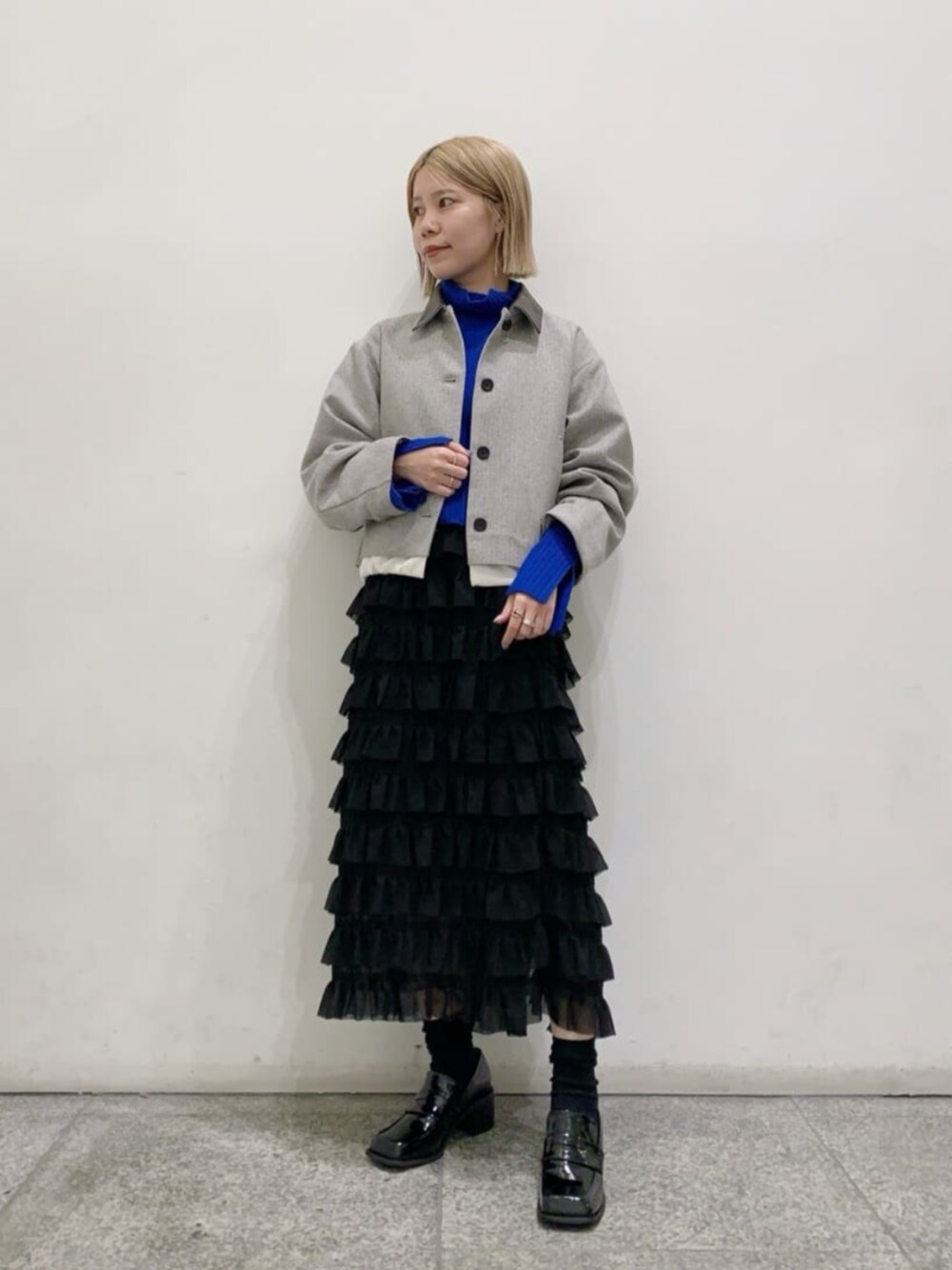 ブラック系のスカート、ブラック系のローファー、グレー系のブルゾンを着用したレディースの秋コーディネートの1枚目の写真