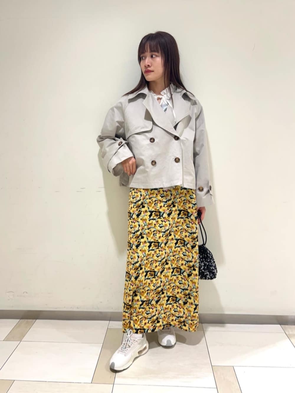 ホワイト系のトレンチコート、ブラック系のショルダーバッグ、イエロー系のスカートを着用したレディースの冬コーディネートの1枚目の写真