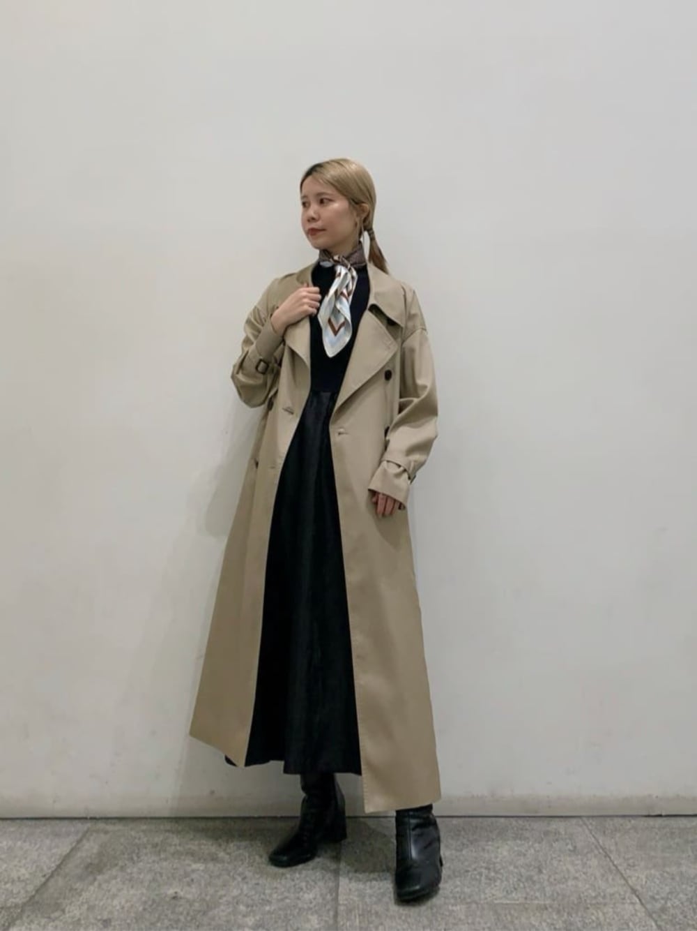 ブラック系のワンピース、ベージュ系のトレンチコートを着用したレディースの春コーディネートの1枚目の写真