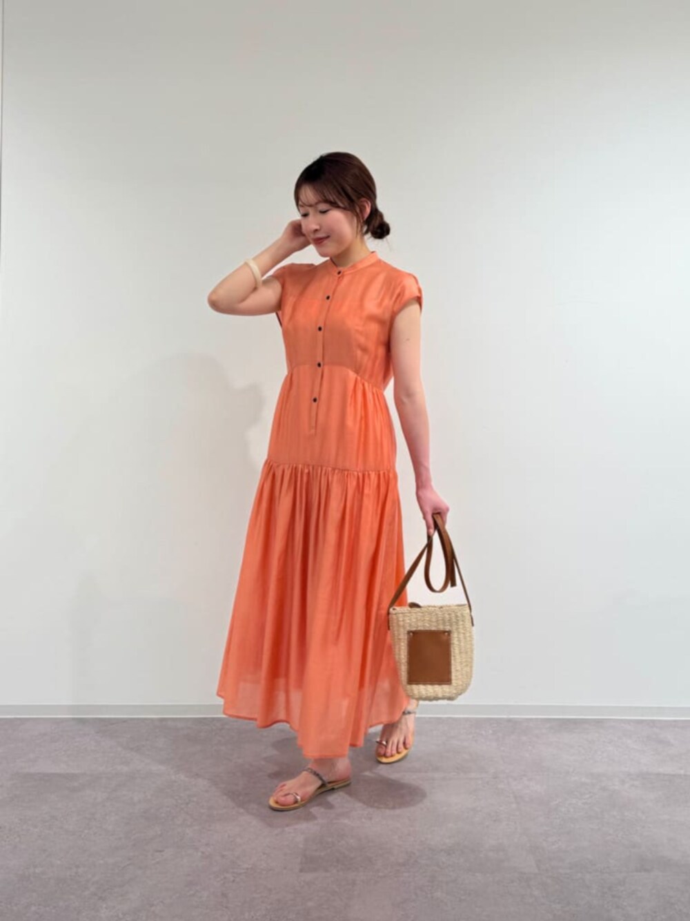 オレンジ系のワンピースを着用したレディースの春コーディネートの1枚目の写真