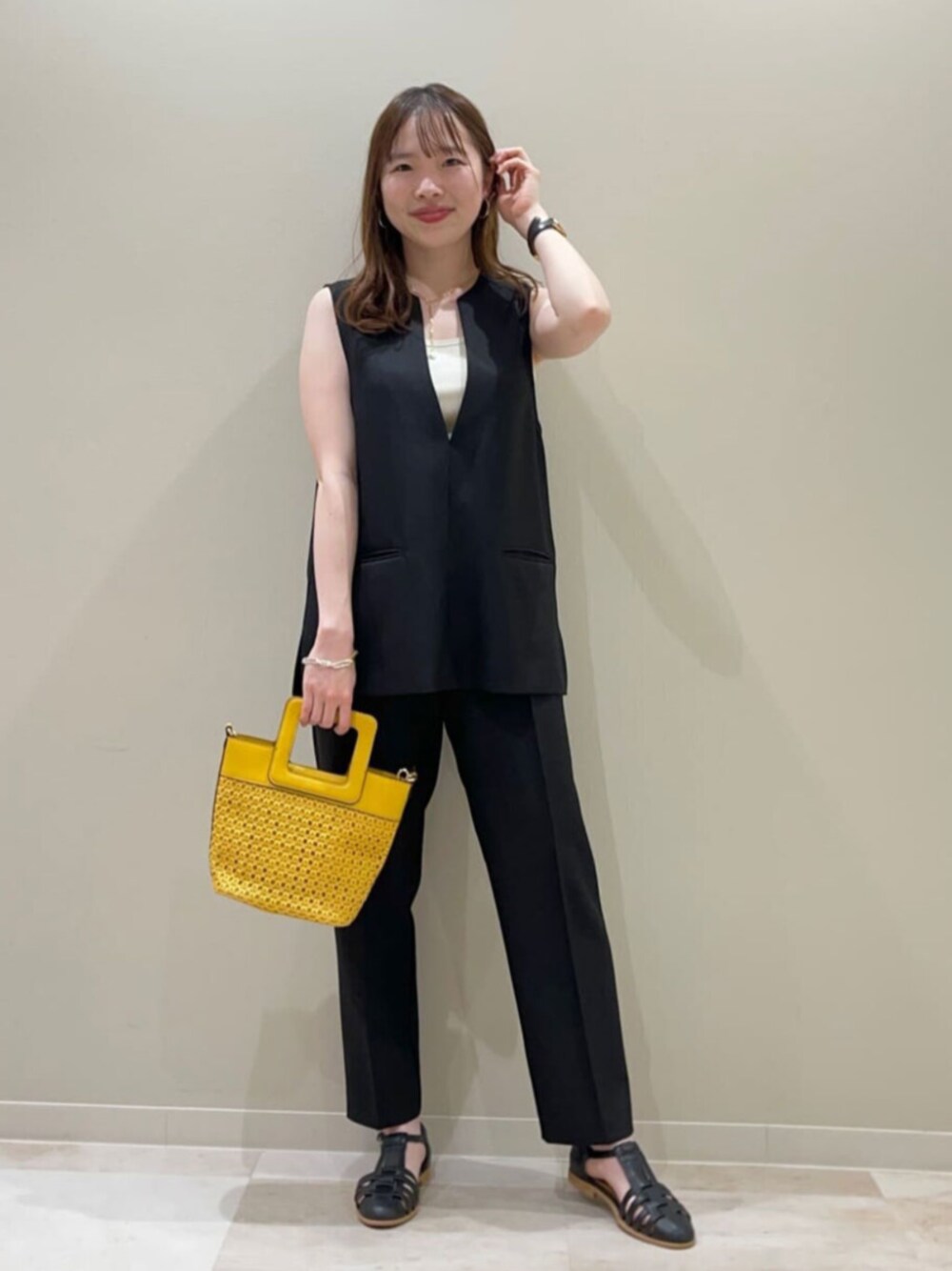 イエロー系のトートバッグ、ブラック系のセットアップを着用したレディースの夏コーディネートの1枚目の写真