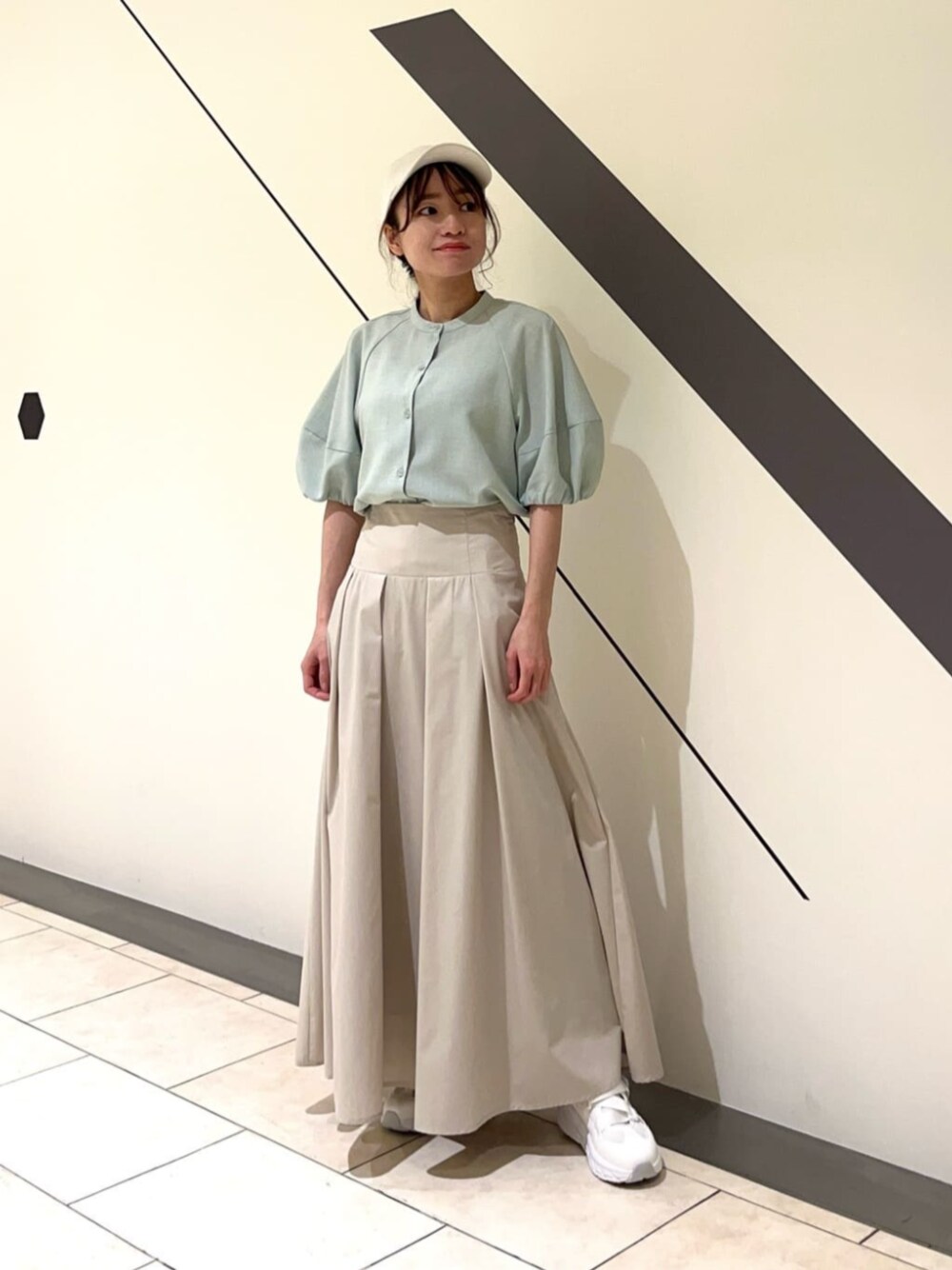 ホワイト系のスニーカー、グリーン系のシャツ/ブラウス、ベージュ系のスカートを着用したレディースの春コーディネートの1枚目の写真