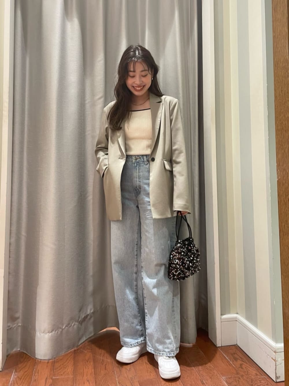 ブラック系のショルダーバッグ、ブルー系のデニムパンツ、ベージュ系のテーラードジャケットを着用したレディースの春コーディネートの1枚目の写真