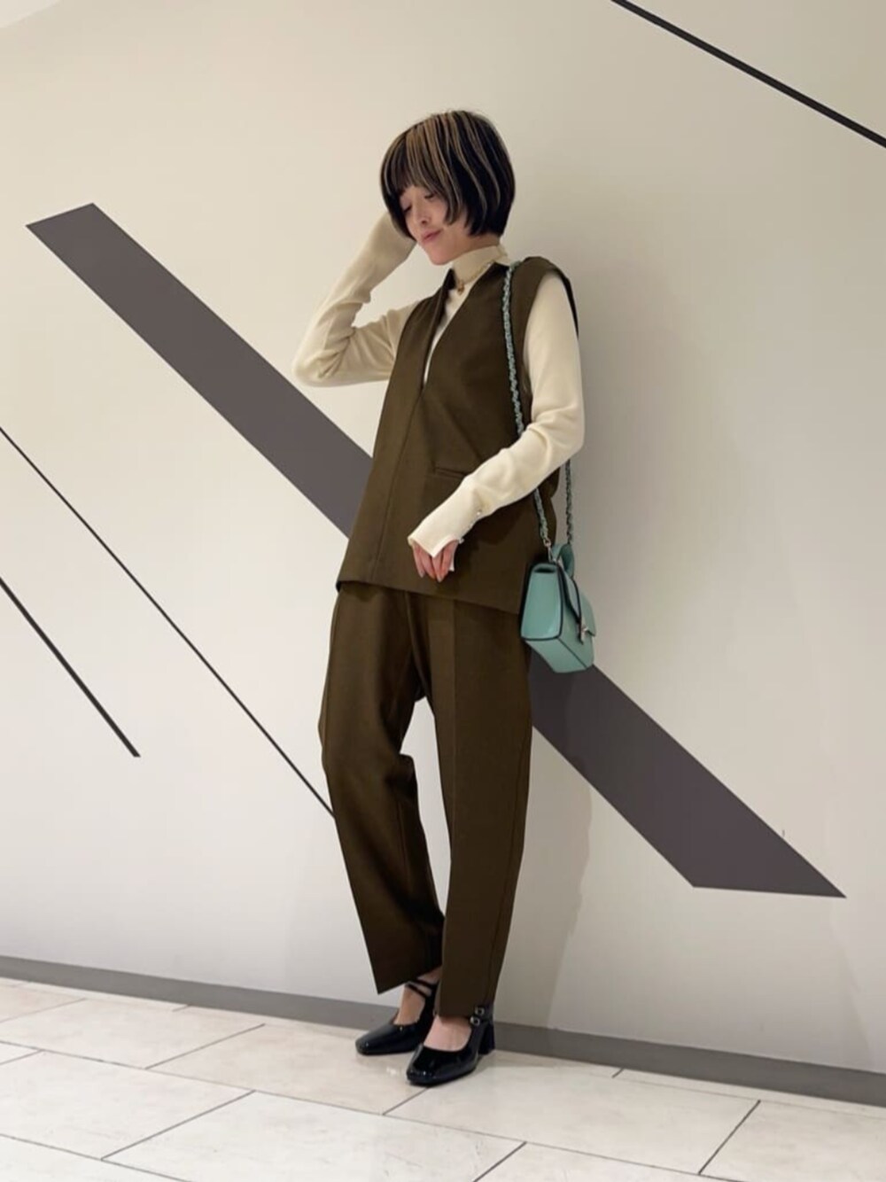 ブラック系のパンプス、ブラウン系のセットアップ、ホワイト系のニット/セーターを着用したレディースの冬コーディネートの1枚目の写真