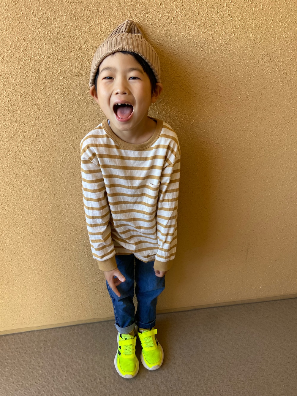 ホワイト系のトップス、ブルー系のパンツ、イエロー系のスニーカーを着用したキッズの秋コーディネートの1枚目の写真
