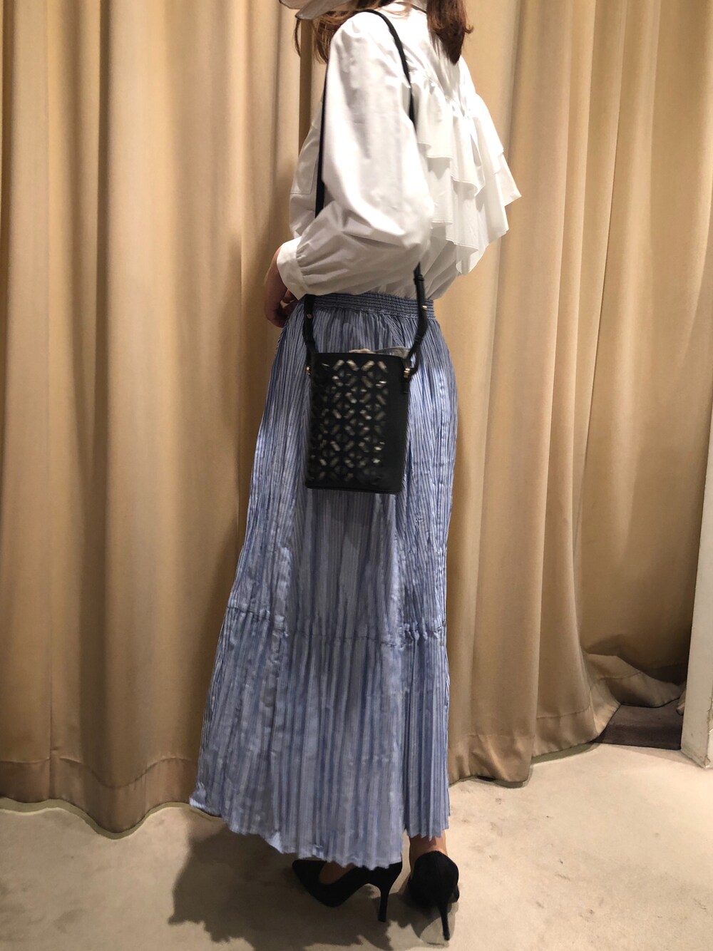 ブルー系のスカート、ホワイト系のシャツ/ブラウス、ブラック系のバッグを着用したレディースの春コーディネートの1枚目の写真