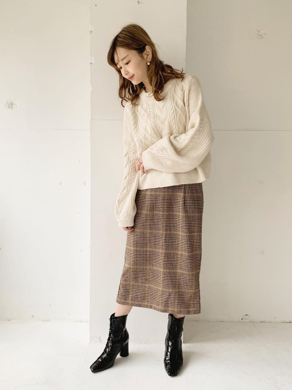 ブラウン系のスカート、ホワイト系のニット/セーター、ブラック系のブーツを着用したレディースの秋コーディネートの1枚目の写真