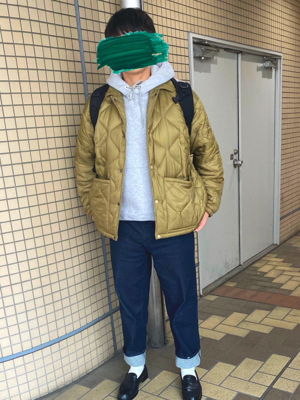 グレー系のパーカー、グリーン系のジャケット/アウター、ブルー系のデニムパンツを着用したメンズの春コーディネートの1枚目の写真