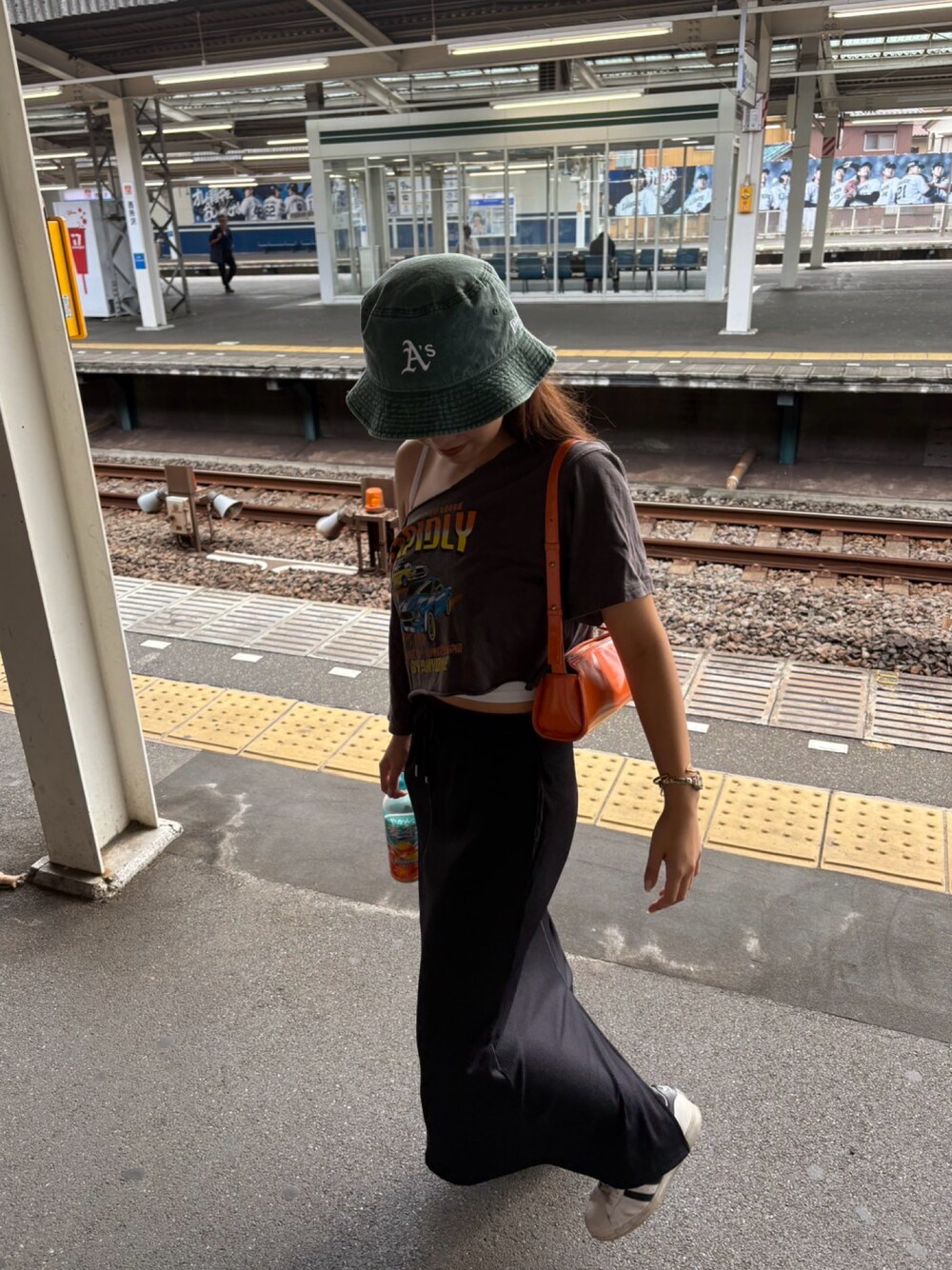 ブラック系のスカート、オレンジ系のバッグ、ホワイト系のスニーカーを着用したレディースの秋コーディネートの1枚目の写真