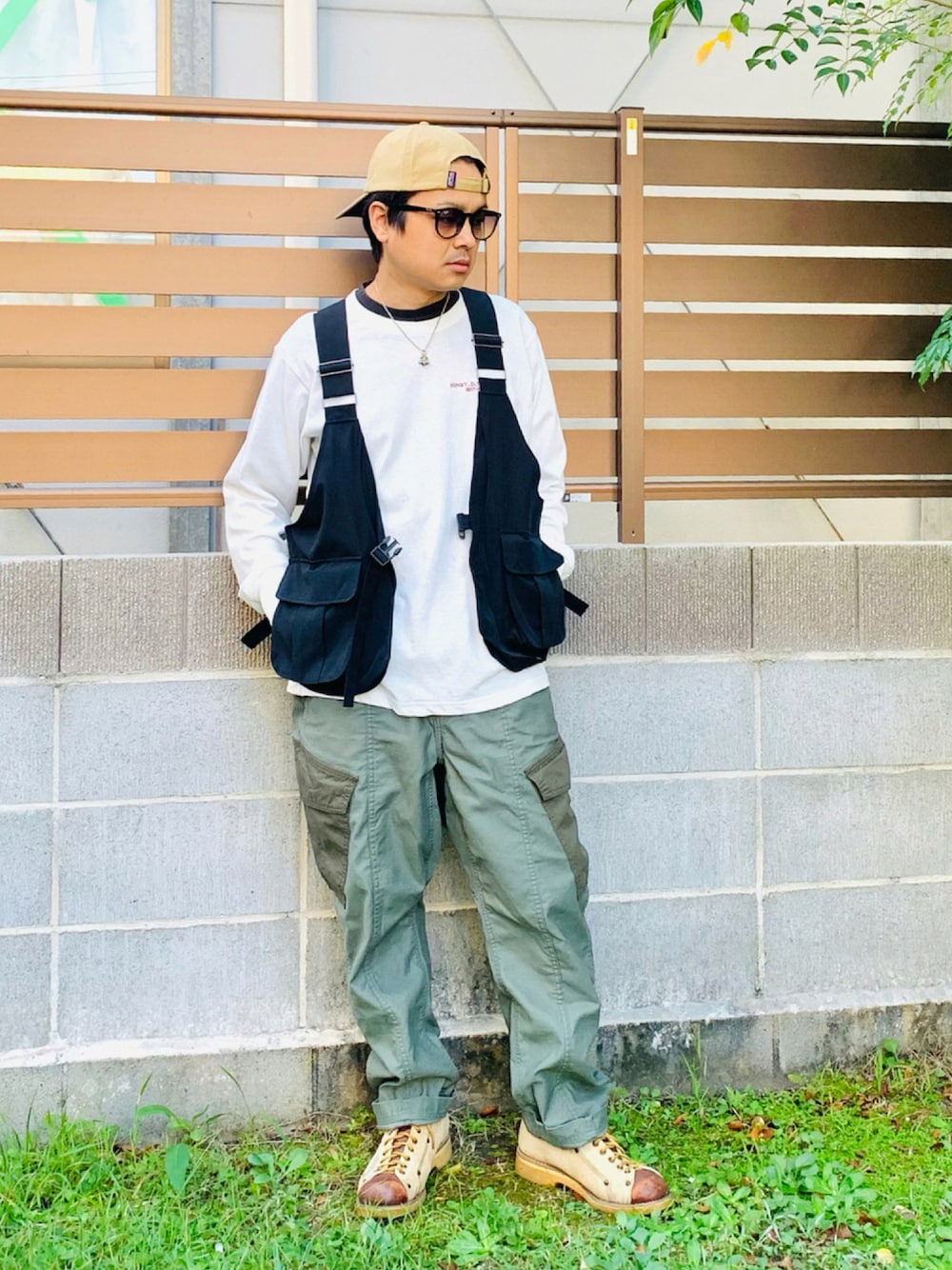 ブラック系のベスト、ホワイト系のTシャツ/カットソー、グリーン系のカーゴパンツを着用したメンズの秋コーディネートの1枚目の写真