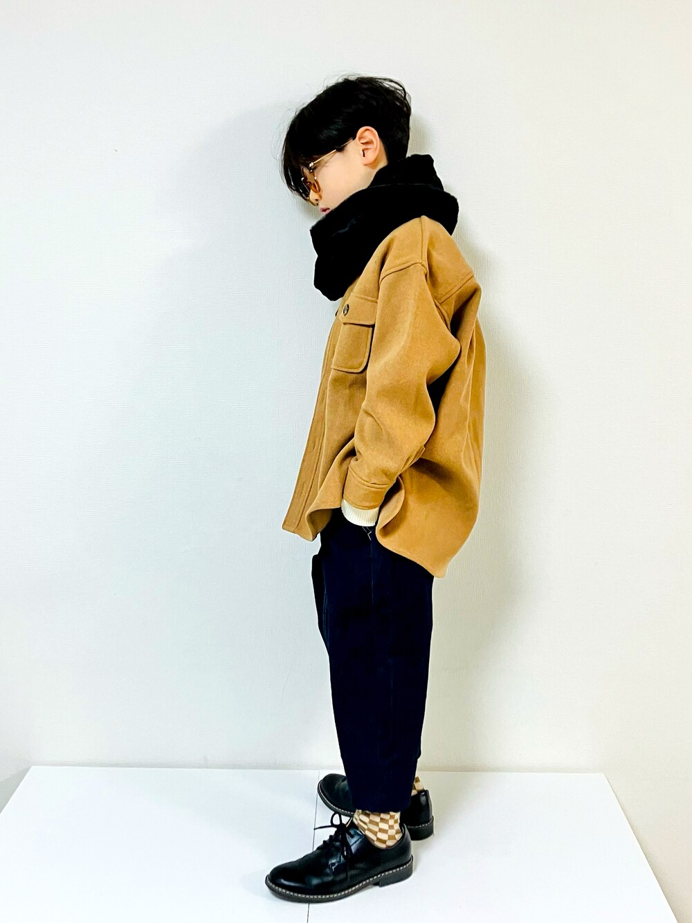 イエロー系のミリタリージャケット、ブルー系のデニムパンツ、ブラック系のローファーを着用したキッズの冬コーディネートの1枚目の写真