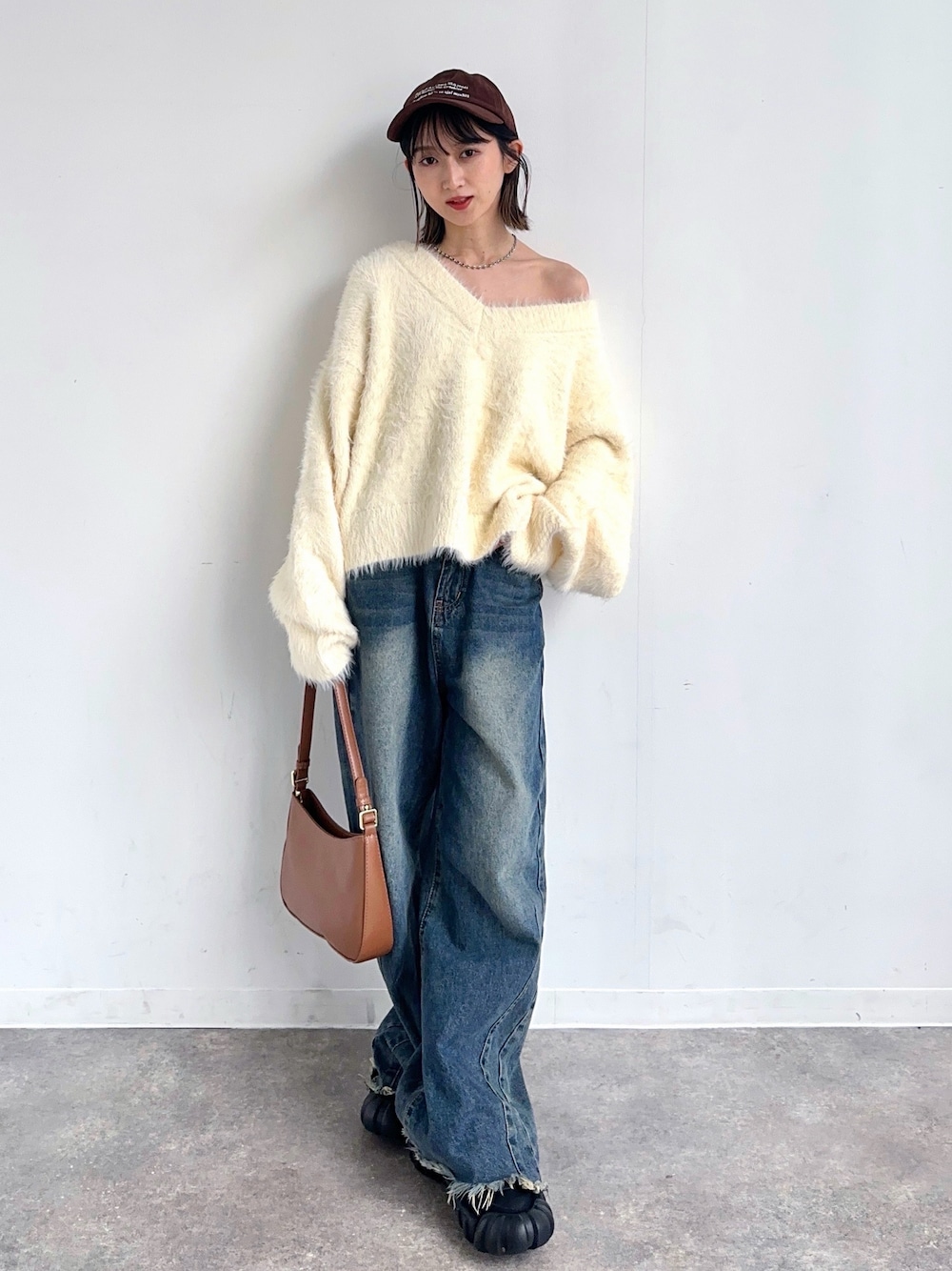 グリーン系のデニムパンツ、ホワイト系のニット/セーター、ブラック系のスニーカーを着用したレディースの秋コーディネートの1枚目の写真