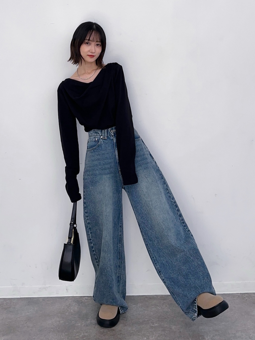 ブルー系のデニムパンツ、ブラック系のハンドバッグ、ブラック系のTシャツ/カットソーを着用したレディースの秋コーディネートの1枚目の写真
