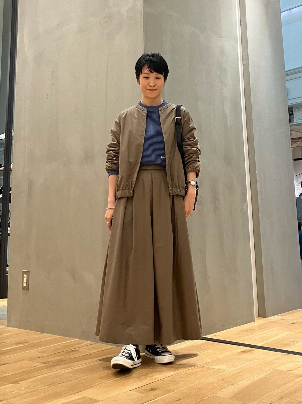 ブルー系のTシャツ/カットソー、ブラウン系のブルゾン、ブラウン系のスカートを着用したレディースの秋コーディネートの1枚目の写真