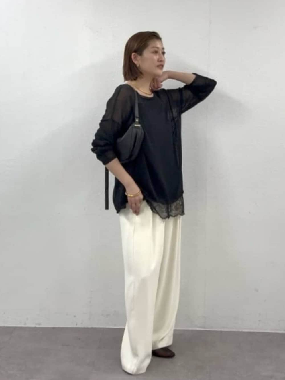 ホワイト系のスラックス、ブラック系のニット/セーター、ブラック系のキャミソールを着用したレディースの春コーディネートの1枚目の写真