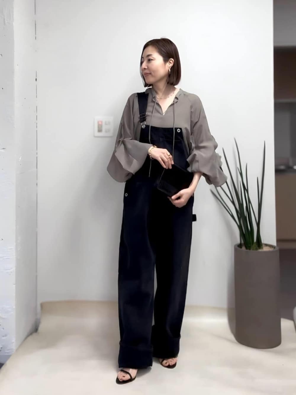 グリーン系のシャツ/ブラウス、ブラック系のサロペット/オーバーオール、ブラック系のサンダルを着用したレディースの春コーディネートの1枚目の写真