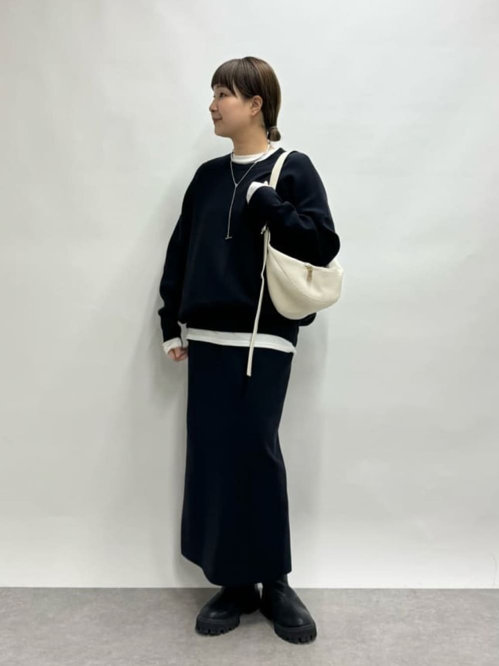 ホワイト系のボディバッグ/ウエストポーチ、ブルー系のニット/セーター、ホワイト系のTシャツ/カットソーを着用したレディースの冬コーディネートの1枚目の写真