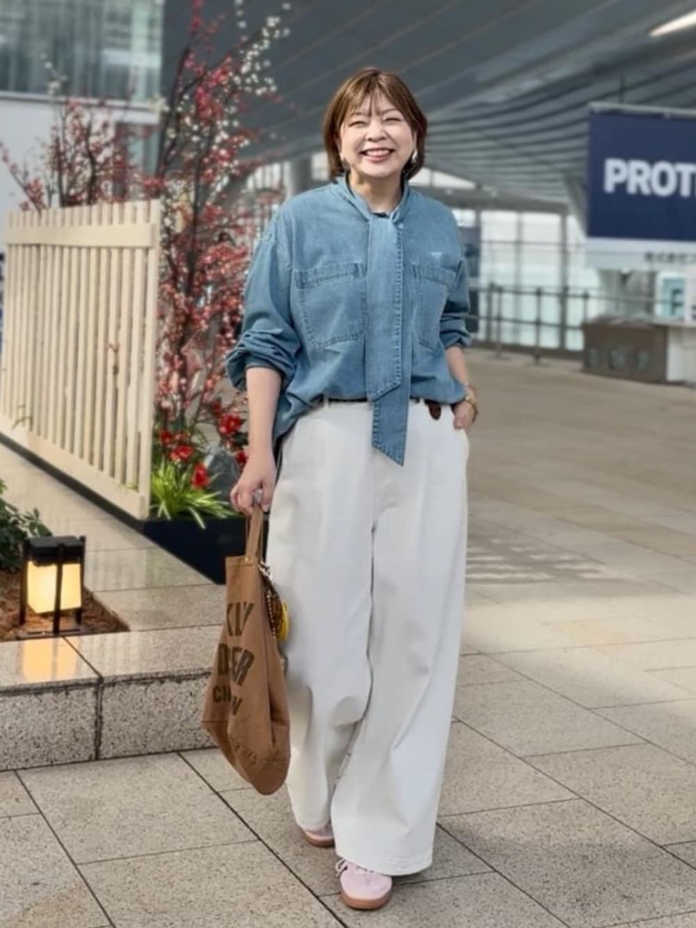 ホワイト系のデニムパンツ、ブルー系のシャツ/ブラウス、ブラウン系のベルトを着用したレディースの春コーディネートの1枚目の写真