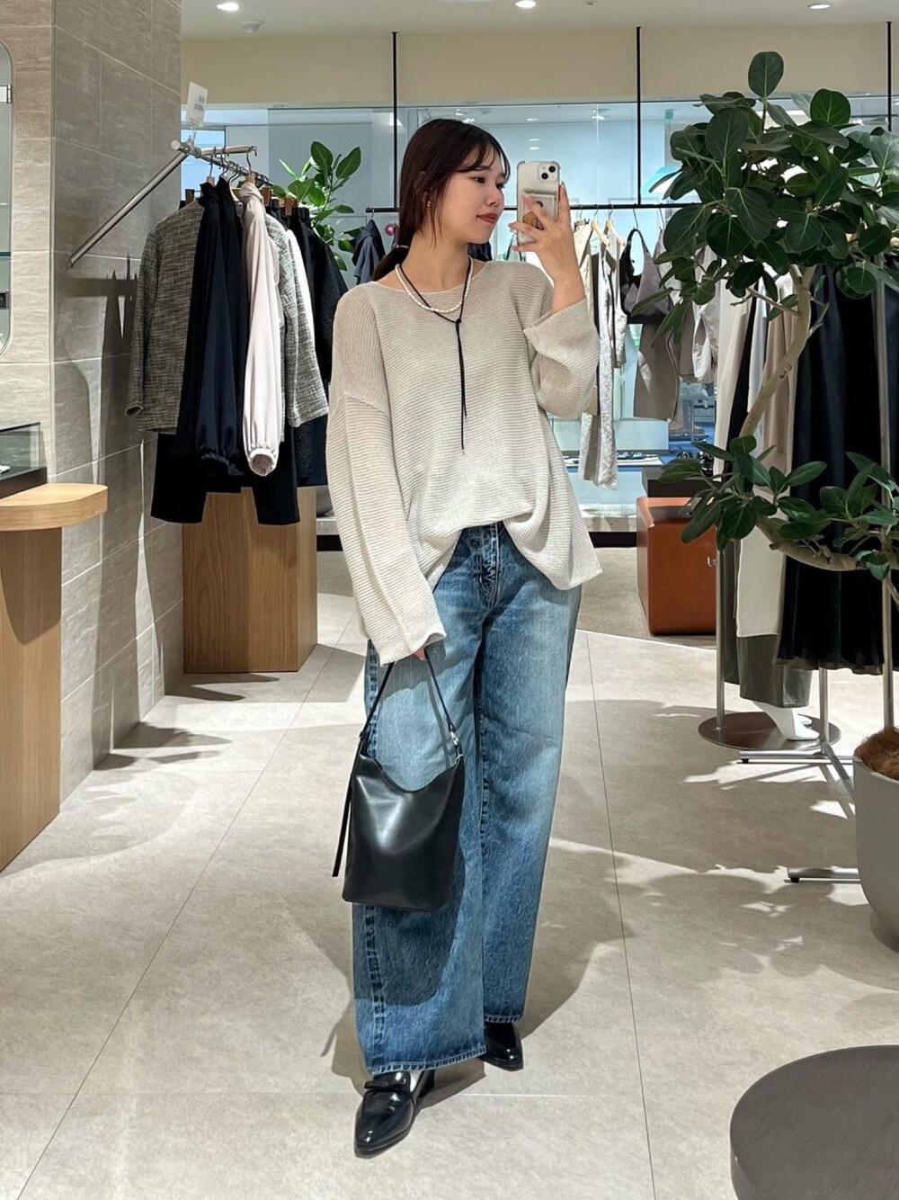 グレー系のニット/セーター、ブルー系のデニムパンツ、ブラック系のハンドバッグを着用したレディースの冬コーディネートの1枚目の写真