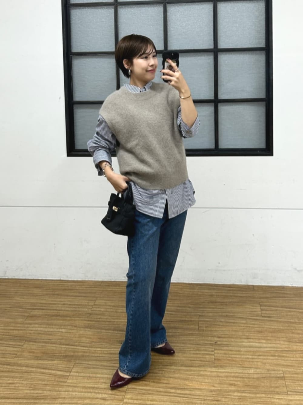 ブラック系のトートバッグ、レッド系のパンプス、ブルー系のシャツ/ブラウスを着用したレディースの秋コーディネートの1枚目の写真