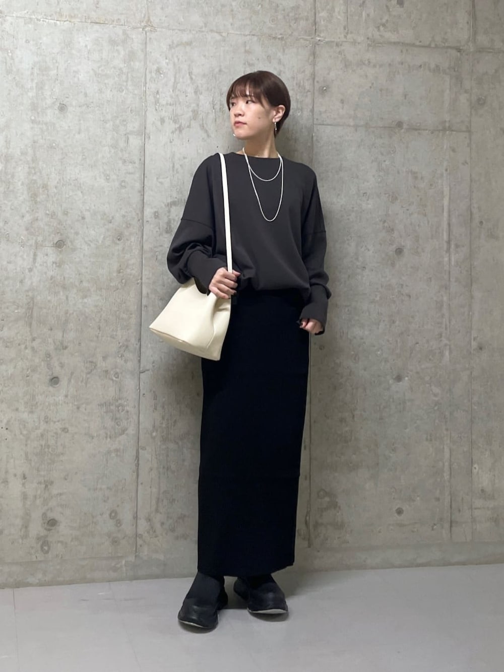 グレー系のTシャツ/カットソー、ブラック系のスカート、ブラック系のブーツを着用したレディースの冬コーディネートの1枚目の写真