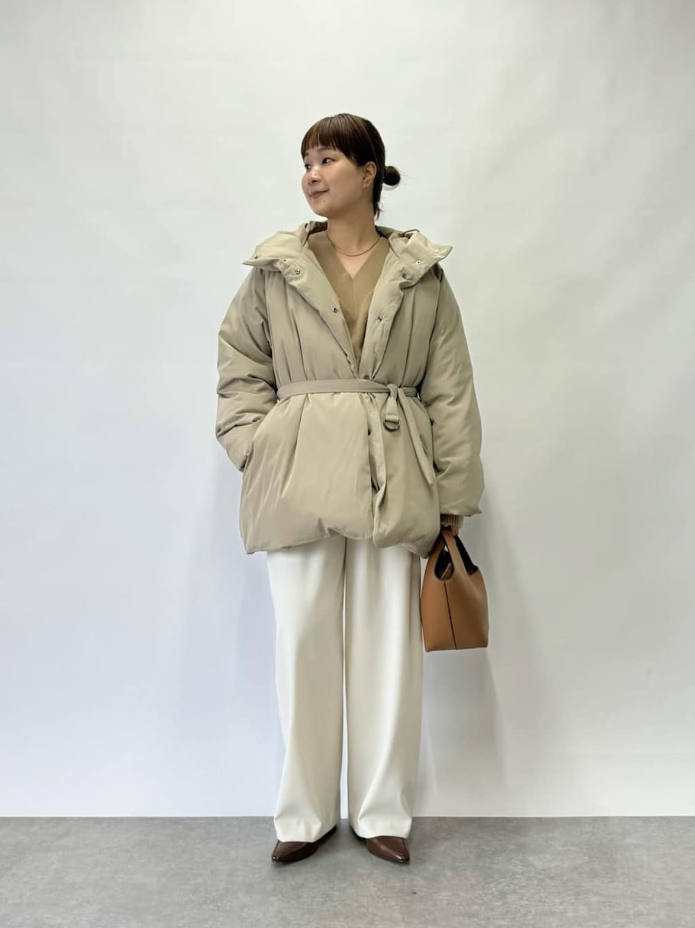 ベージュ系のダウンジャケット/コート、イエロー系のハンドバッグ、ホワイト系のその他パンツを着用したレディースの冬コーディネートの1枚目の写真