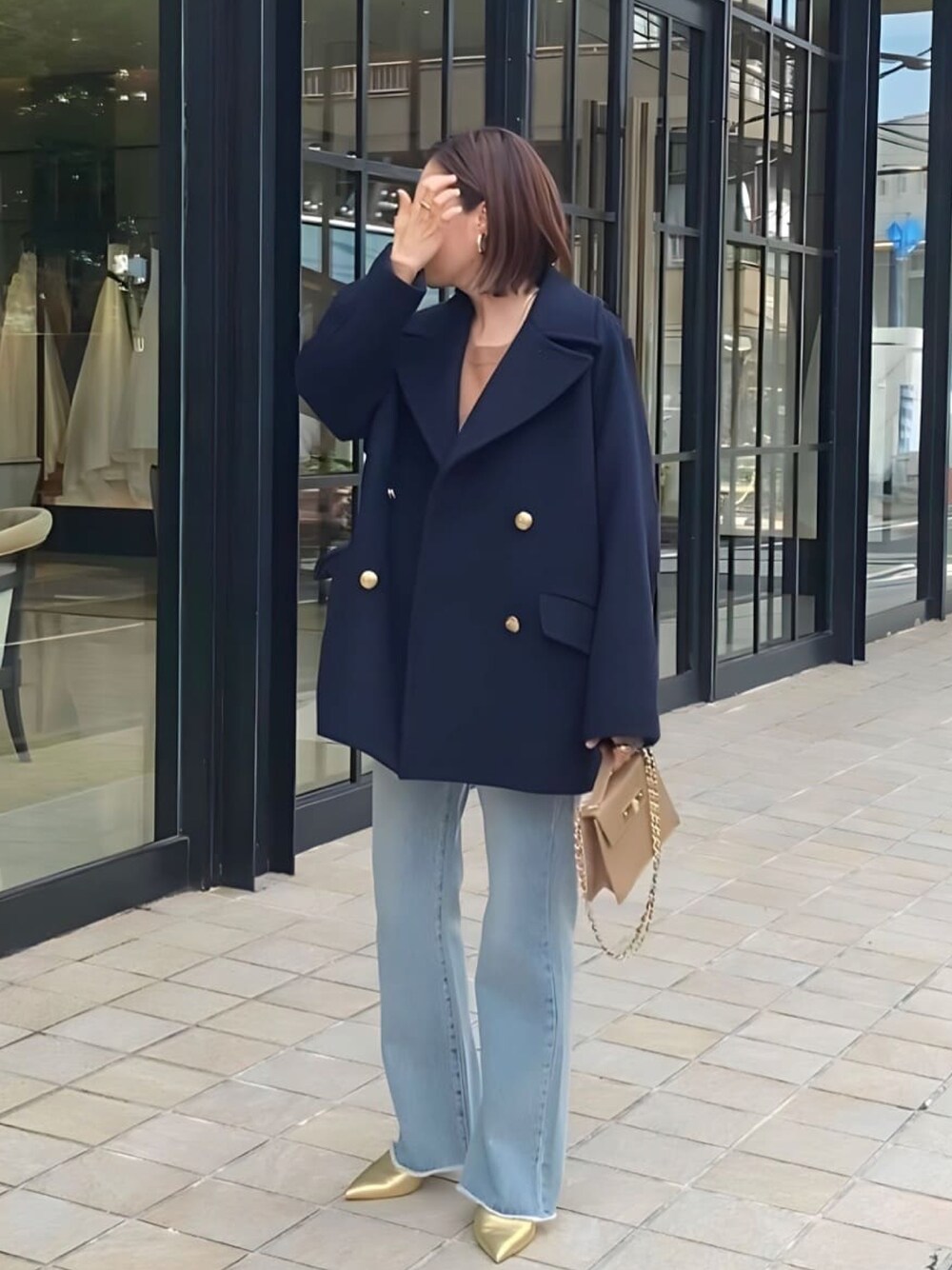 ブルー系のピーコート、ブルー系のデニムパンツ、ゴールド系のパンプスを着用したレディースの冬コーディネートの1枚目の写真