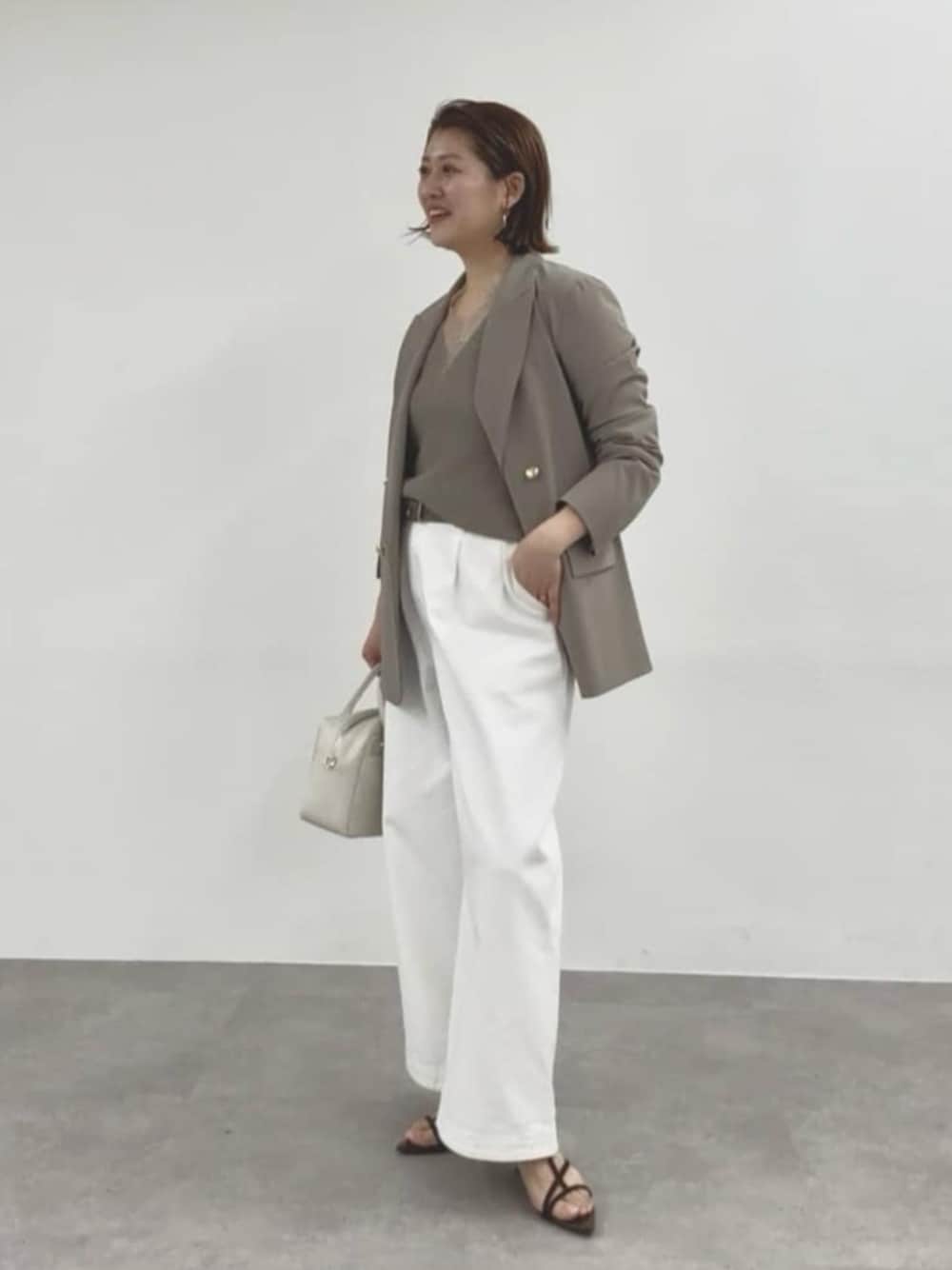 ブラウン系のテーラードジャケット、ホワイト系のデニムパンツ、ホワイト系のボストンバッグを着用したレディースの春コーディネートの1枚目の写真