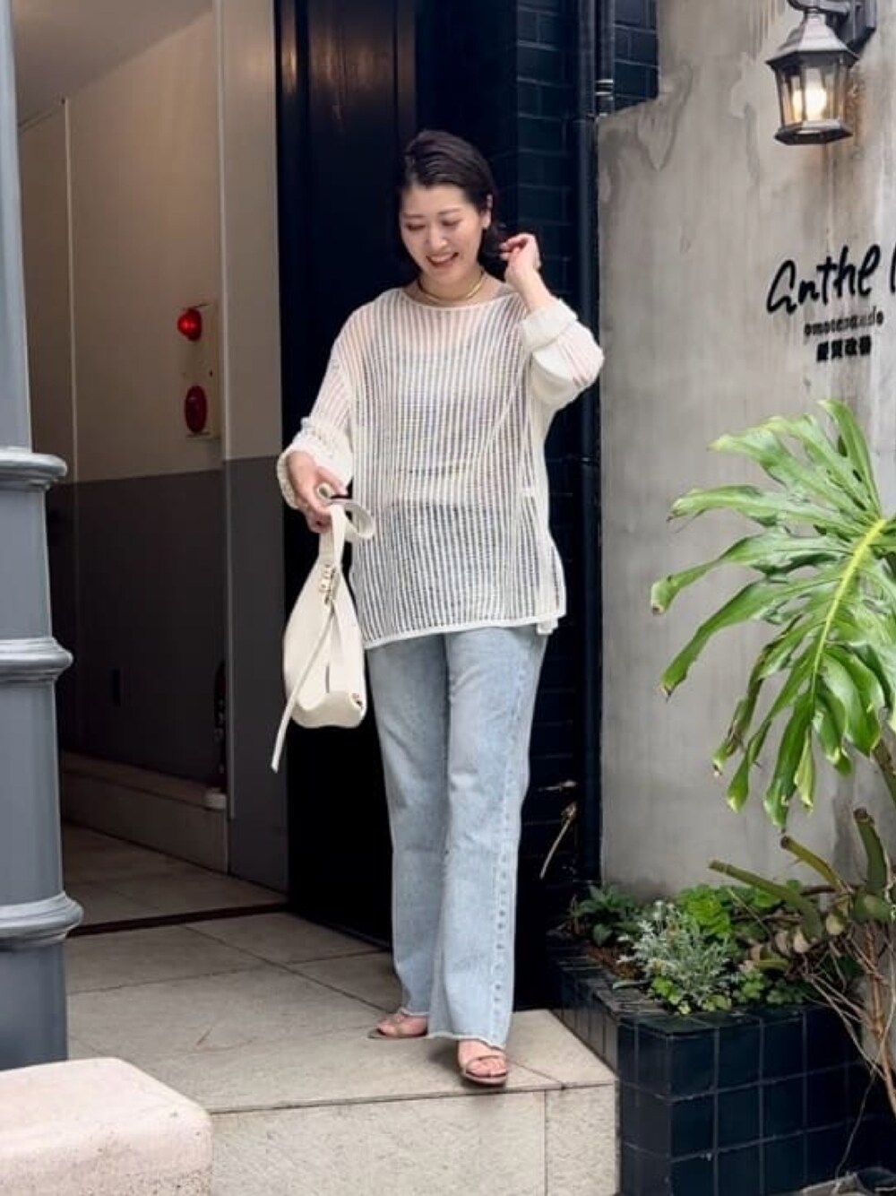 ホワイト系のニット/セーター、ブルー系のデニムパンツ、ホワイト系のボディバッグ/ウエストポーチを着用したレディースの春コーディネートの1枚目の写真