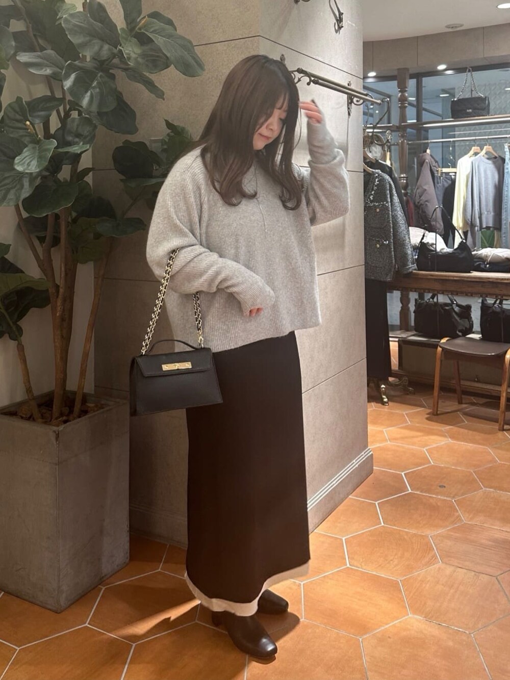 グレー系のニット/セーター、ブラック系のスカート、ブラック系のハンドバッグを着用したレディースの冬コーディネートの1枚目の写真
