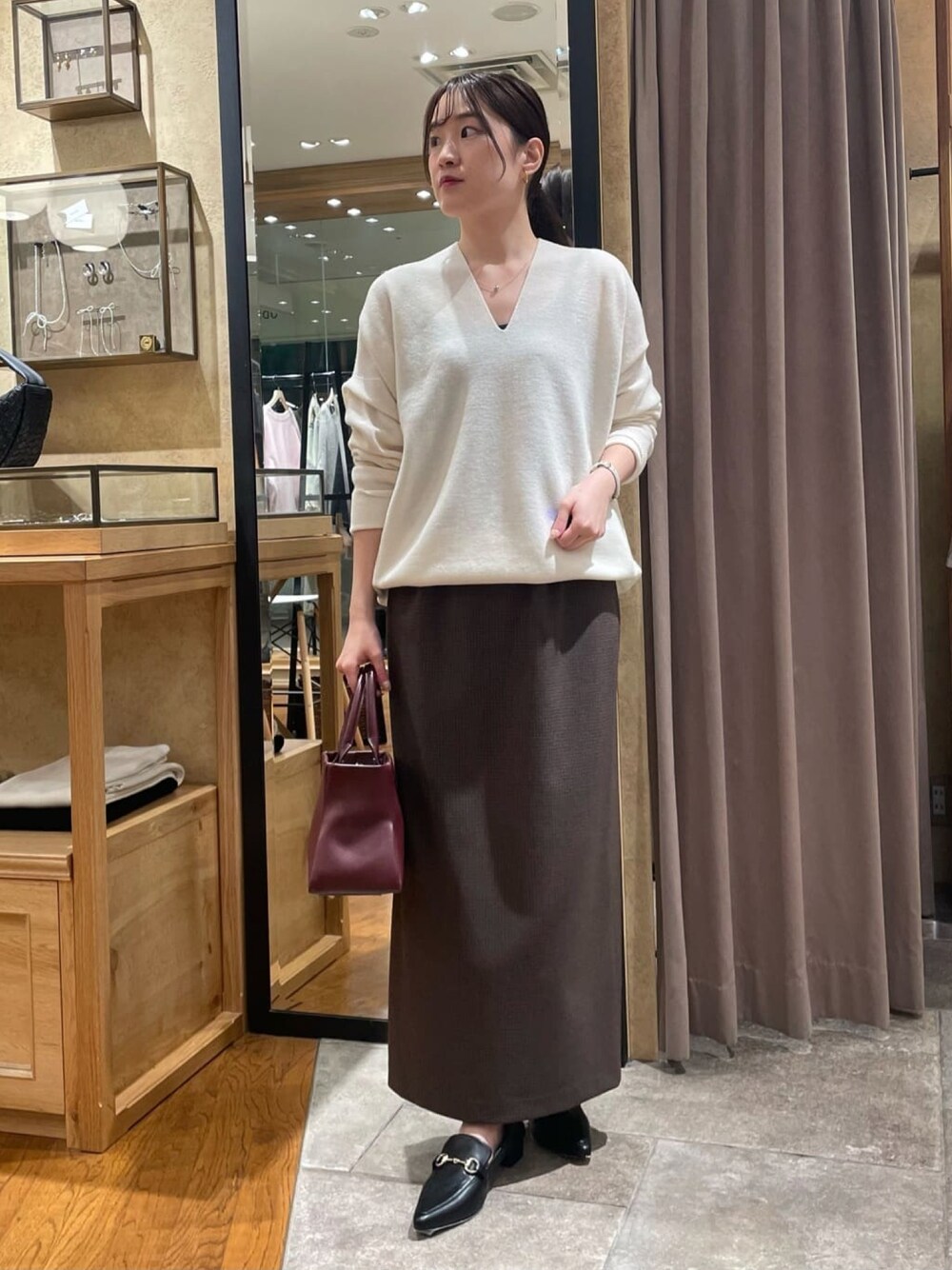ホワイト系のニット/セーター、ブラウン系のスカート、ブラック系のパンプスを着用したレディースの冬コーディネートの1枚目の写真