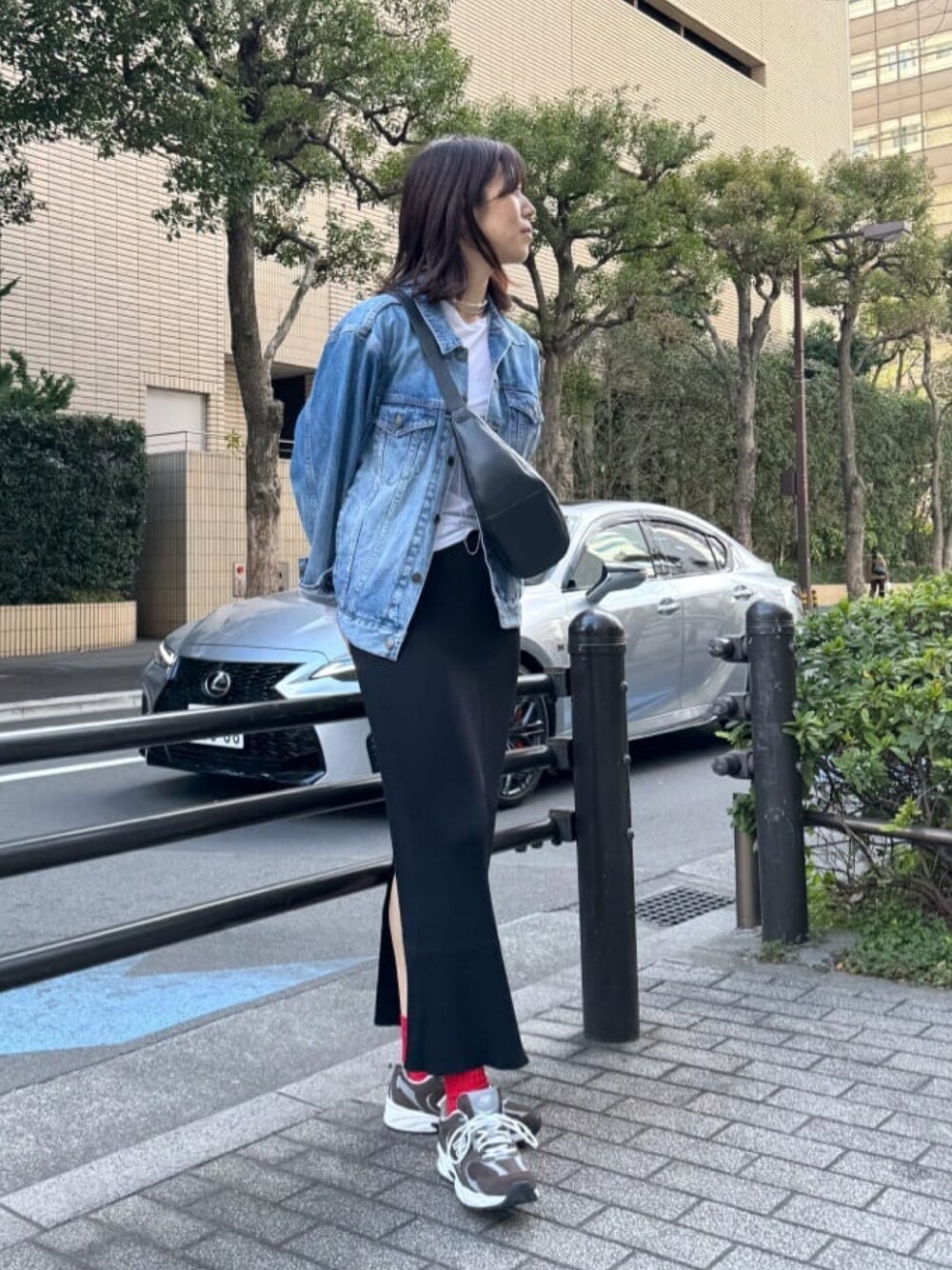 ブラック系のボディバッグ/ウエストポーチ、ブルー系のデニムジャケット、ブラック系のスカートを着用したレディースの冬コーディネートの1枚目の写真