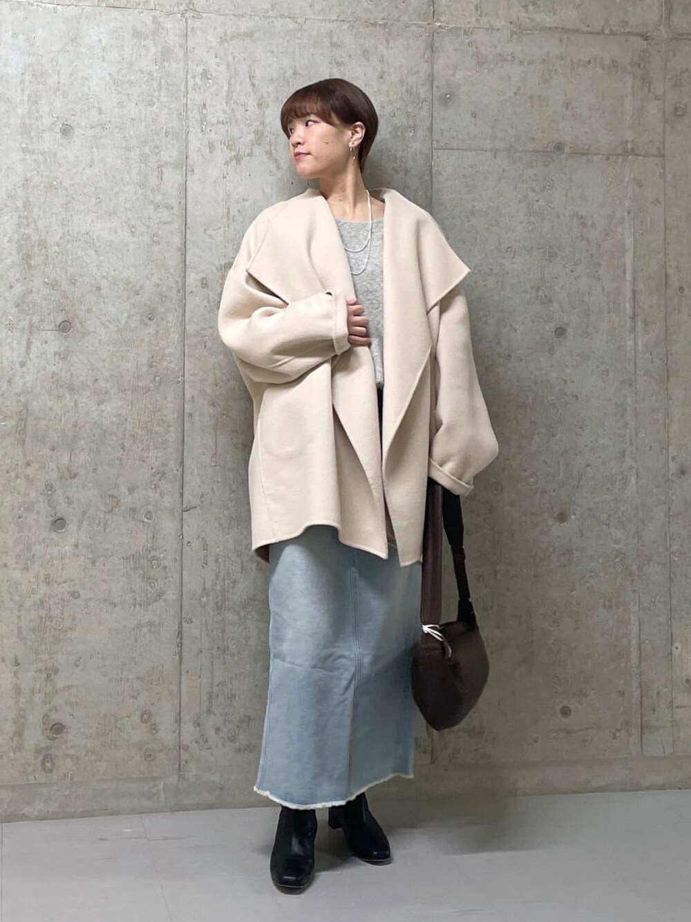 ベージュ系のその他アウター、ブルー系のデニムスカート、グレー系のニット/セーターを着用したレディースの冬コーディネートの1枚目の写真