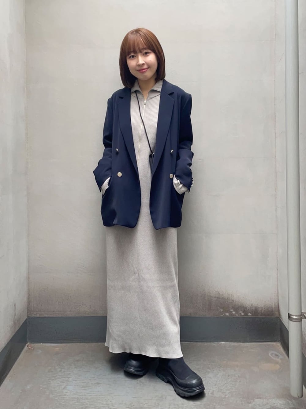 ブルー系のテーラードジャケット、グレー系のワンピース、ブラック系のブーツを着用したレディースの春コーディネートの1枚目の写真