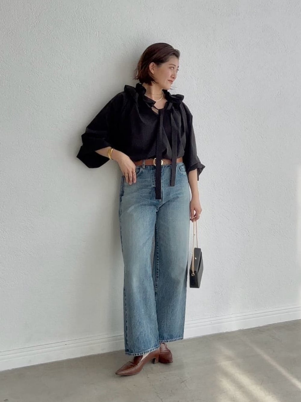 ブラック系のシャツ/ブラウス、ブルー系のデニムパンツ、ブラウン系のローファーを着用したレディースの冬コーディネートの1枚目の写真