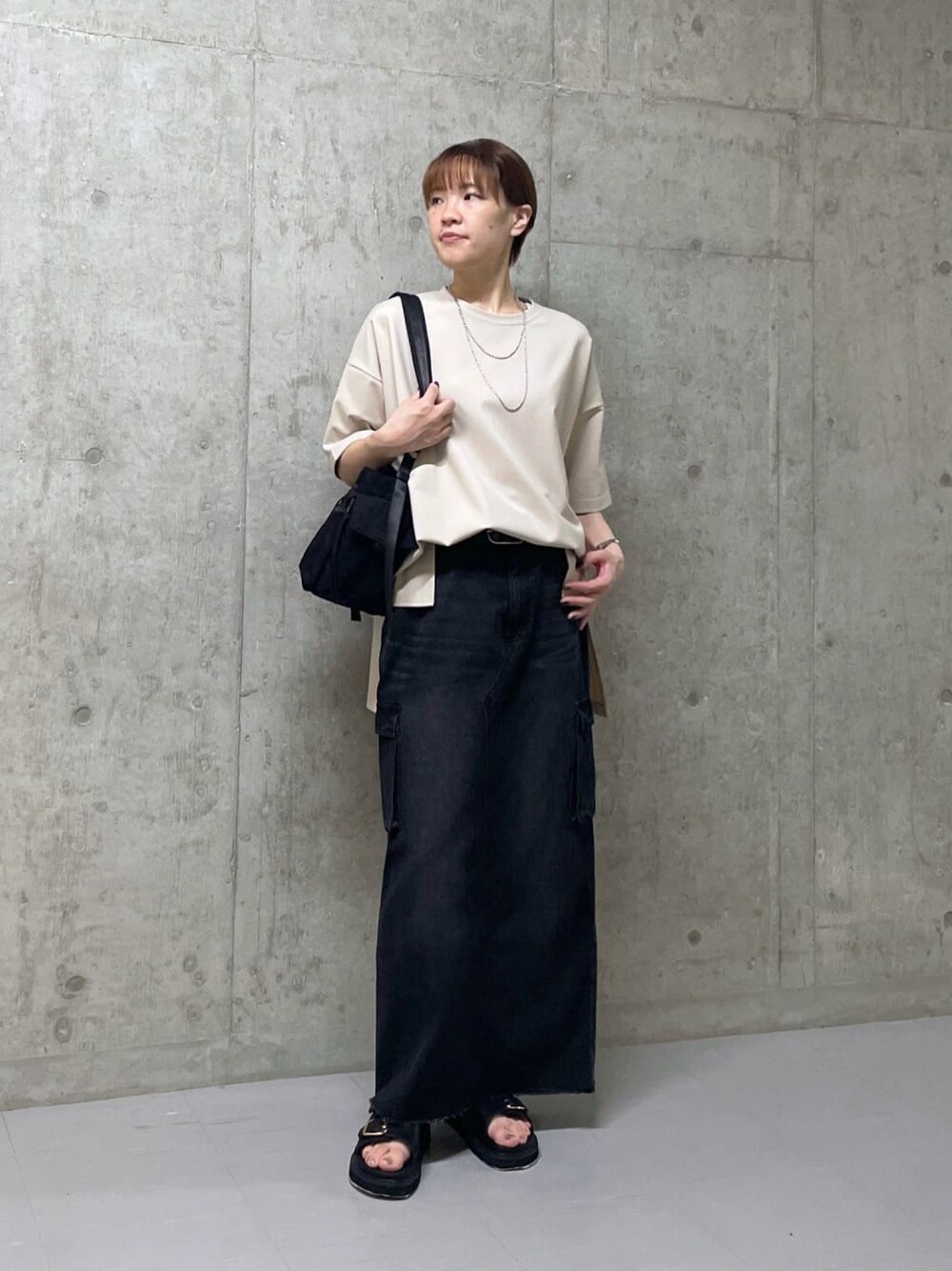 ベージュ系のTシャツ/カットソー、ブラック系のデニムスカート、ブラック系のサンダルを着用したレディースの夏コーディネートの1枚目の写真