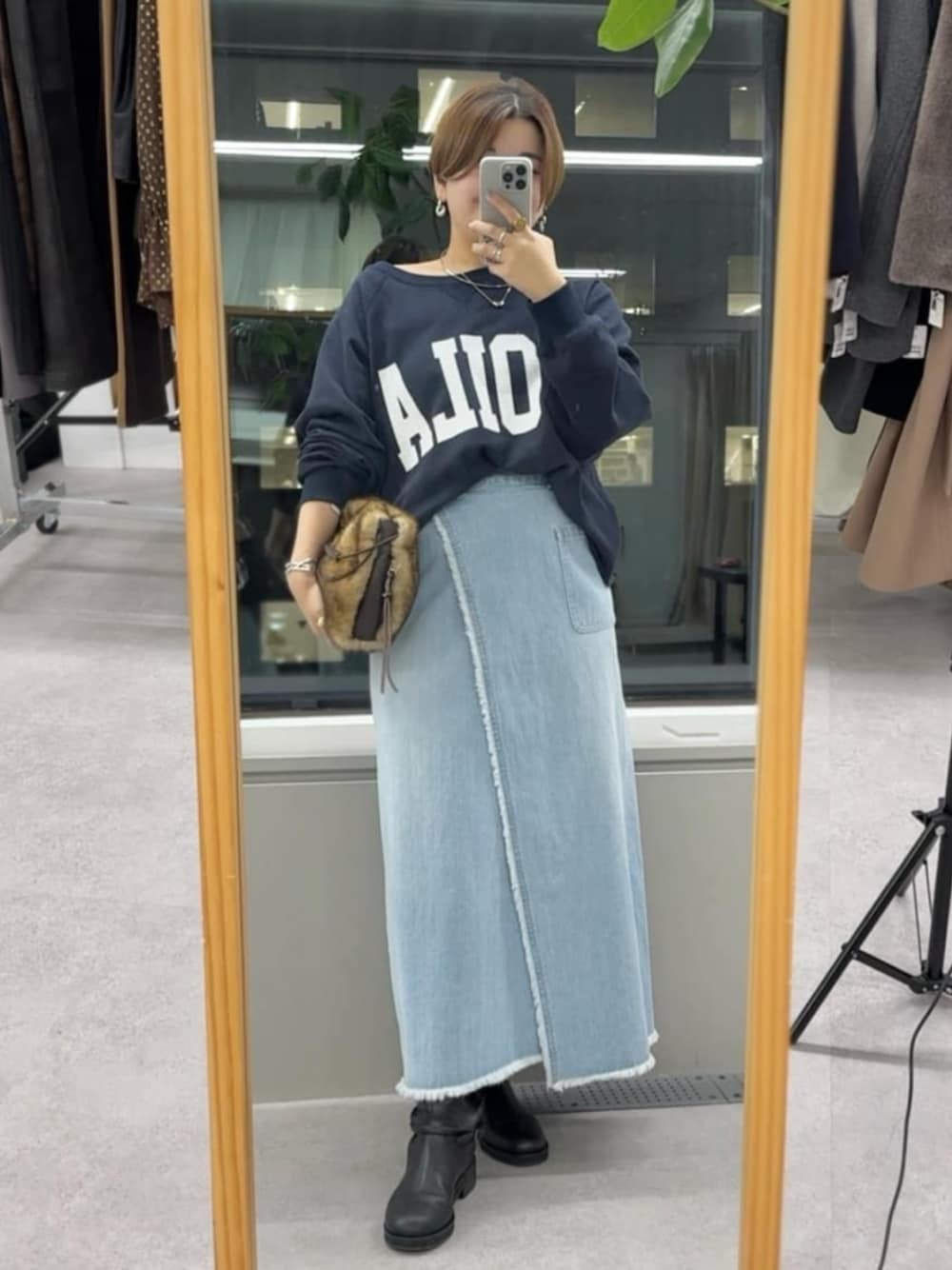 イエロー系のハンドバッグ、ブラック系のブーツ、ブルー系のスウェットを着用したレディースの秋コーディネートの1枚目の写真