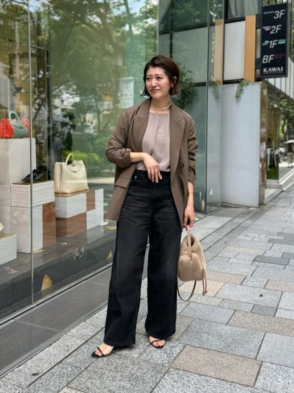 ブラック系のデニムパンツ、ベージュ系のハンドバッグ、ブラック系のサンダルを着用したレディースの夏コーディネートの1枚目の写真