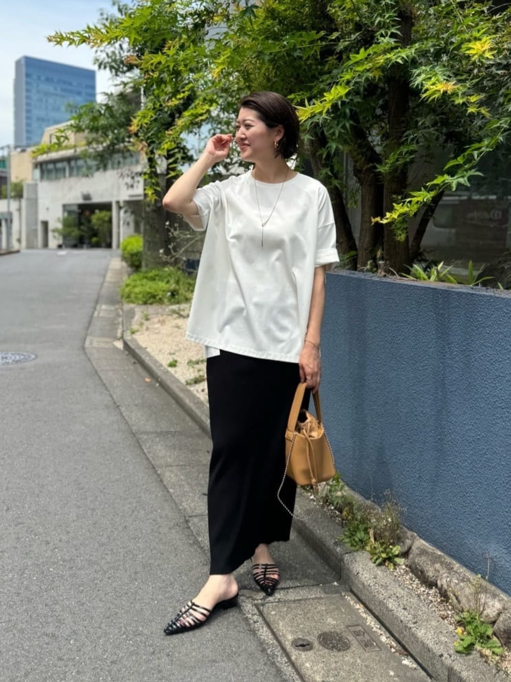 ホワイト系のTシャツ/カットソー、ブラック系のスカートを着用したレディースの春コーディネートの1枚目の写真