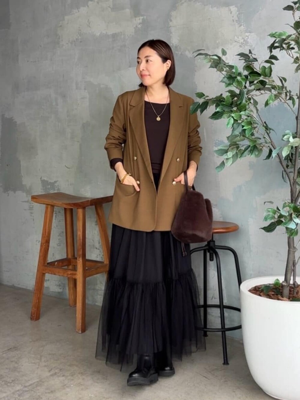 ブラウン系のテーラードジャケット、ブラウン系のTシャツ/カットソー、ブラック系のスカートを着用したレディースの秋コーディネートの1枚目の写真