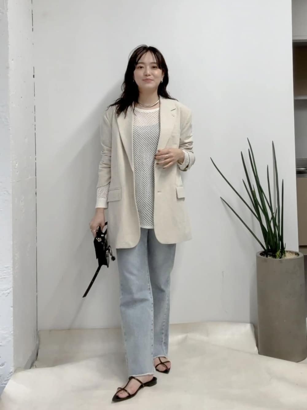 ベージュ系のテーラードジャケット、ホワイト系のニット/セーター、ブルー系のデニムパンツを着用したレディースの冬コーディネートの1枚目の写真