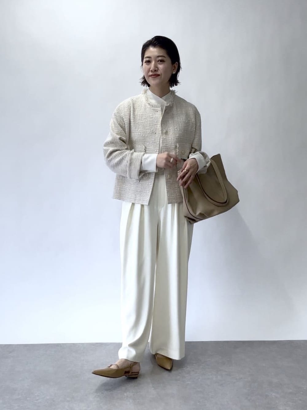 ホワイト系のスラックス、ベージュ系のノーカラージャケット、ベージュ系のトートバッグを着用したレディースの冬コーディネートの1枚目の写真