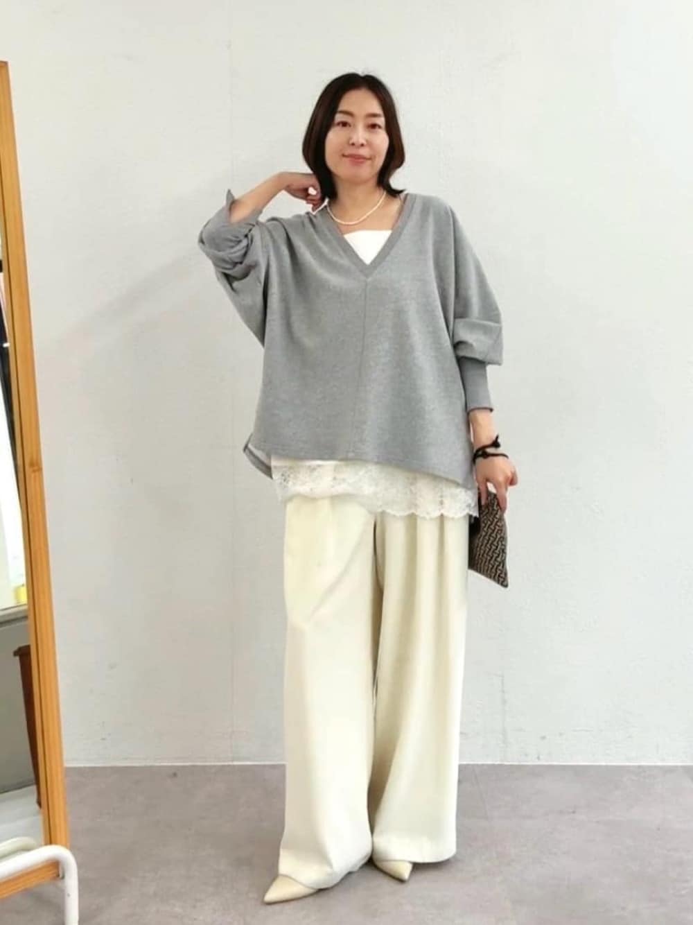 グレー系のスウェット、ホワイト系のスラックス、ホワイト系のキャミソールを着用したレディースの冬コーディネートの1枚目の写真