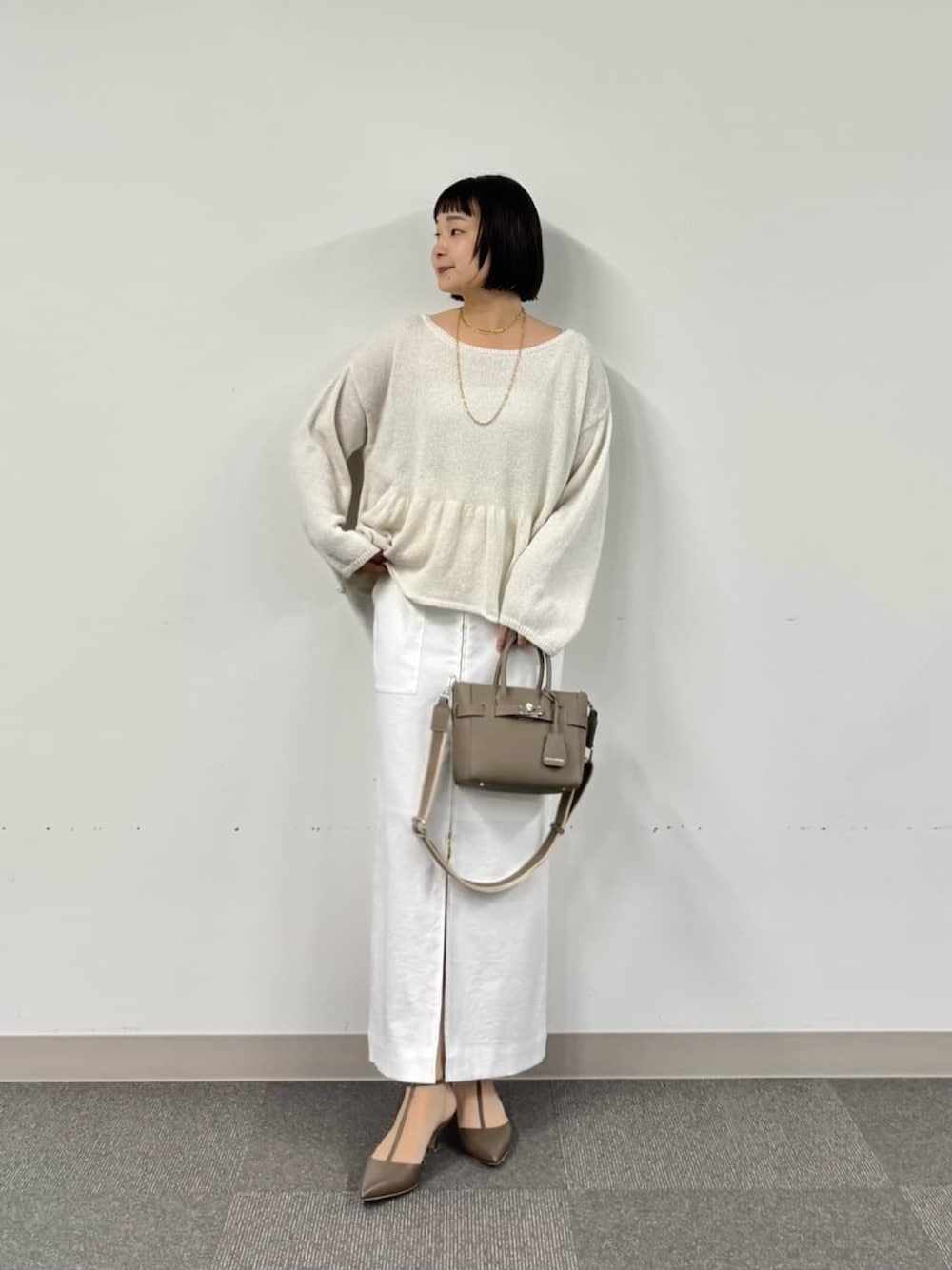 ホワイト系のニット/セーター、グレー系のトートバッグ、ホワイト系のスカートを着用したレディースの冬コーディネートの1枚目の写真