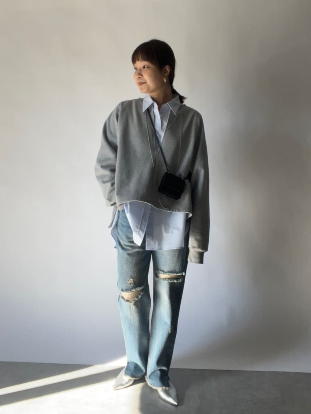 ブラック系のショルダーバッグ、ブルー系のシャツ/ブラウス、ブルー系のデニムパンツを着用したレディースの冬コーディネートの1枚目の写真