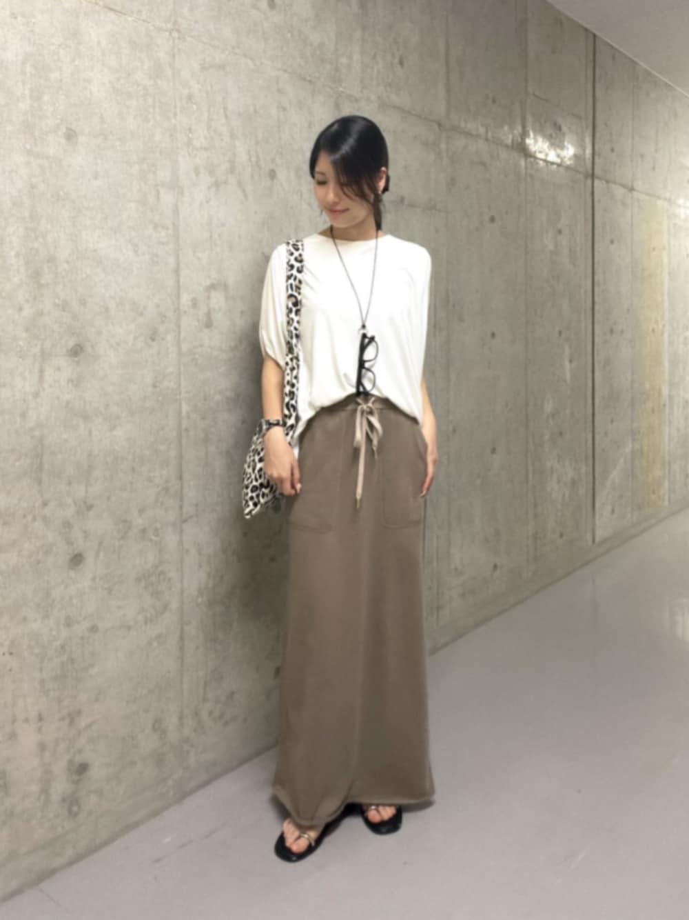 ベージュ系のトートバッグ、ブラウン系のスカート、ホワイト系のTシャツ/カットソーを着用したレディースの夏コーディネートの1枚目の写真