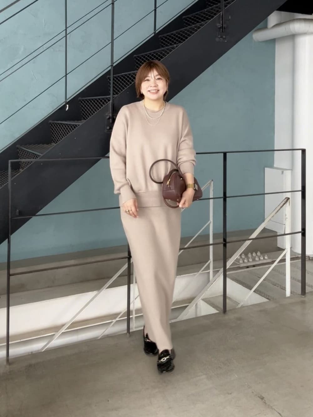 ブラウン系のショルダーバッグ、ブラウン系のニット/セーター、ブラウン系のスカートを着用したレディースの秋コーディネートの1枚目の写真