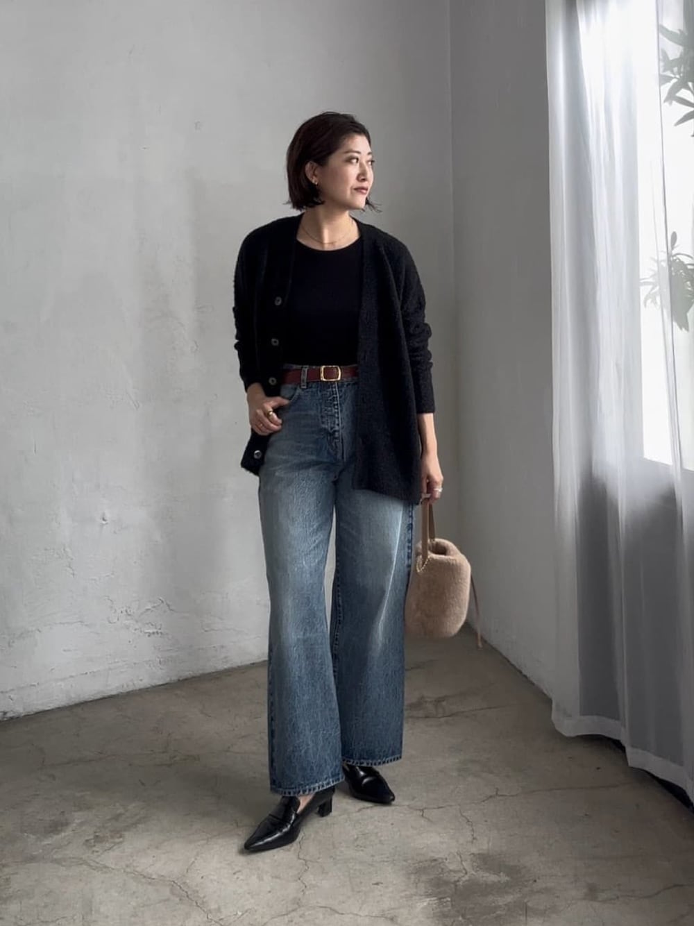 ブラック系のカーディガン/ボレロ、ブラウン系のハンドバッグ、ブラック系のローファーを着用したレディースの秋コーディネートの1枚目の写真